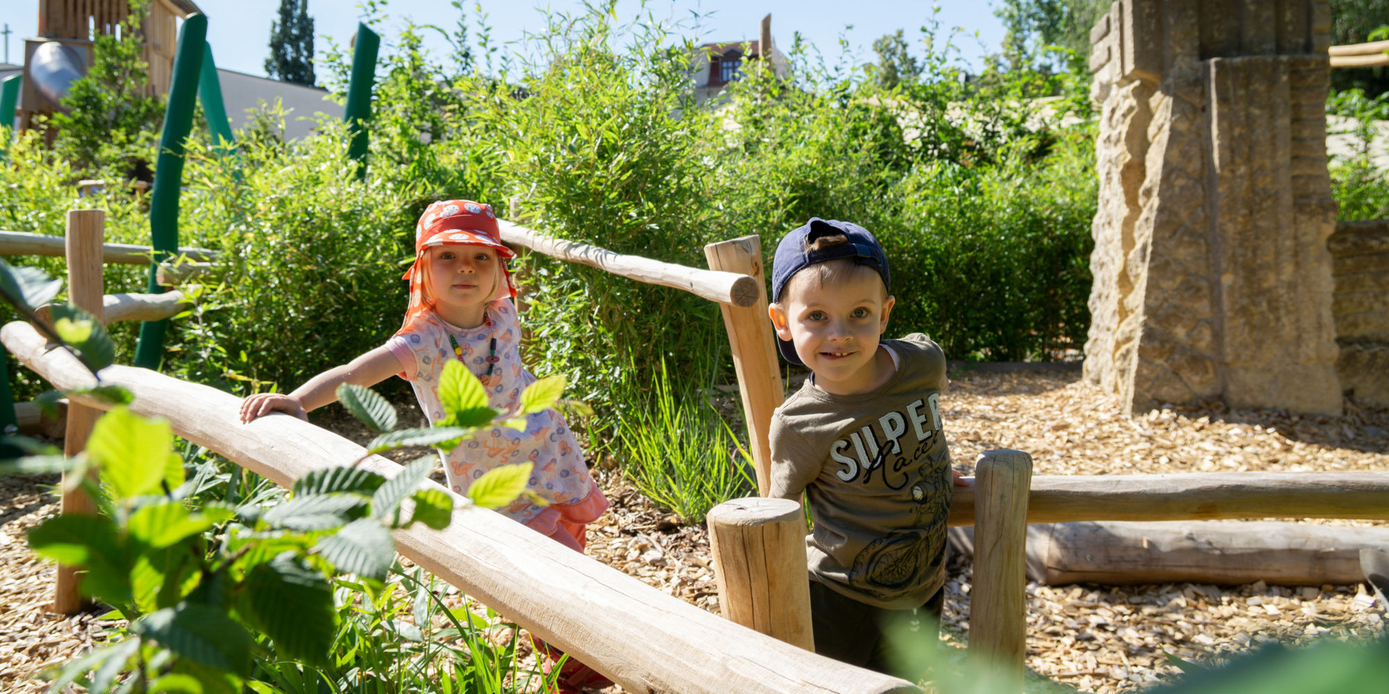 Zwei Kinder im grünem Spielplatz.